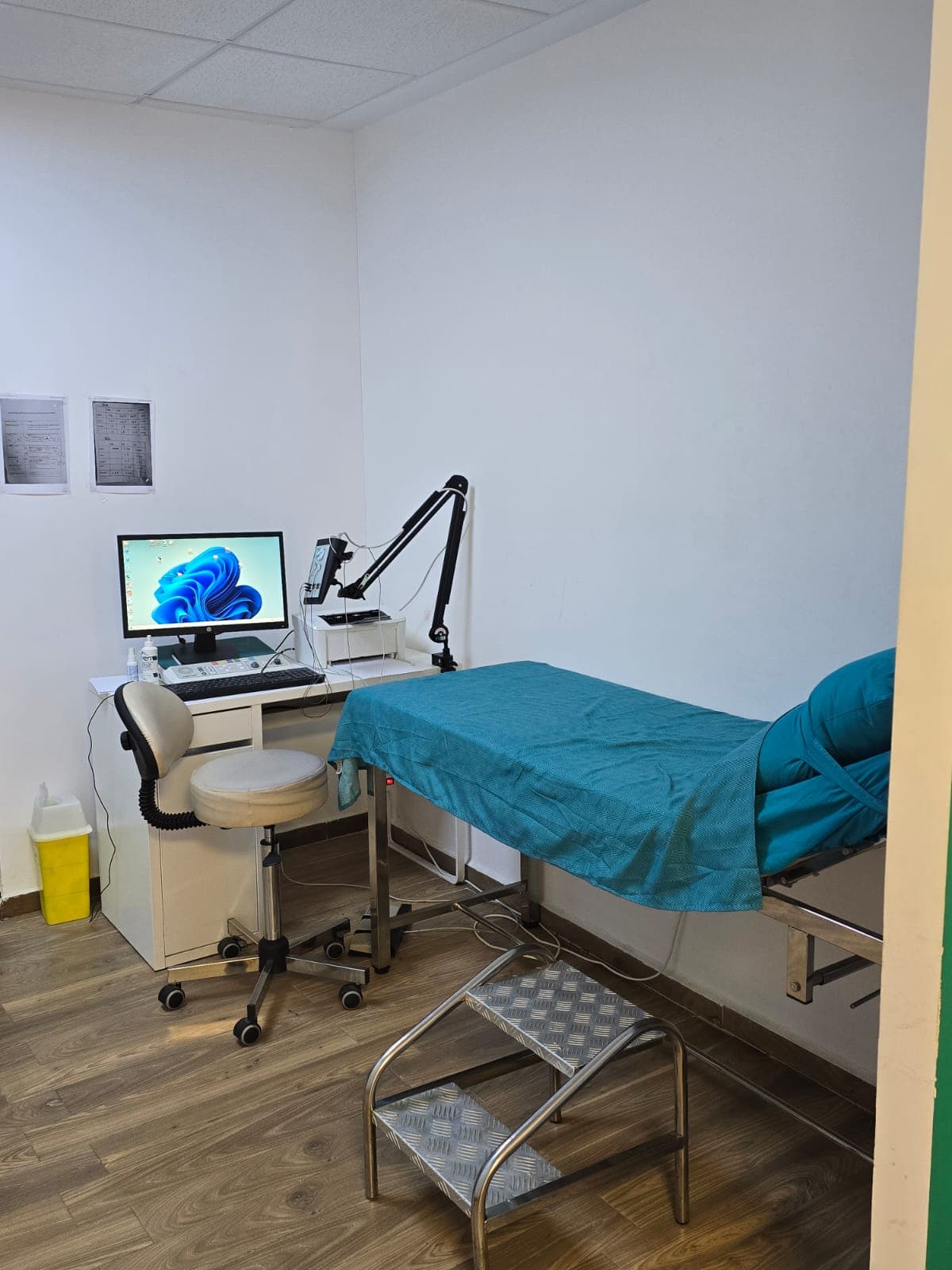 Salle d'examen avec equipement EMG - lit medical turquoise, bras articule